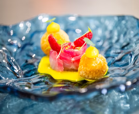 Exklusives Gericht aus frittierten Bällchen, Himbeeren und Speck