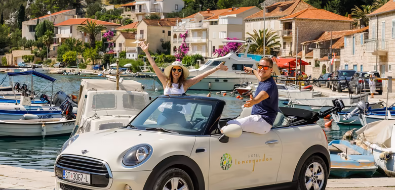 Pärchen sitzt im Cabrio Mini Cooper am Hafen