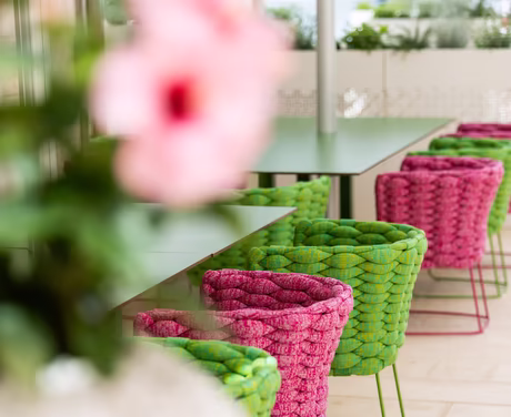 Einblick in das Restaurant von draußen mit Grün / Pinken Stühlen