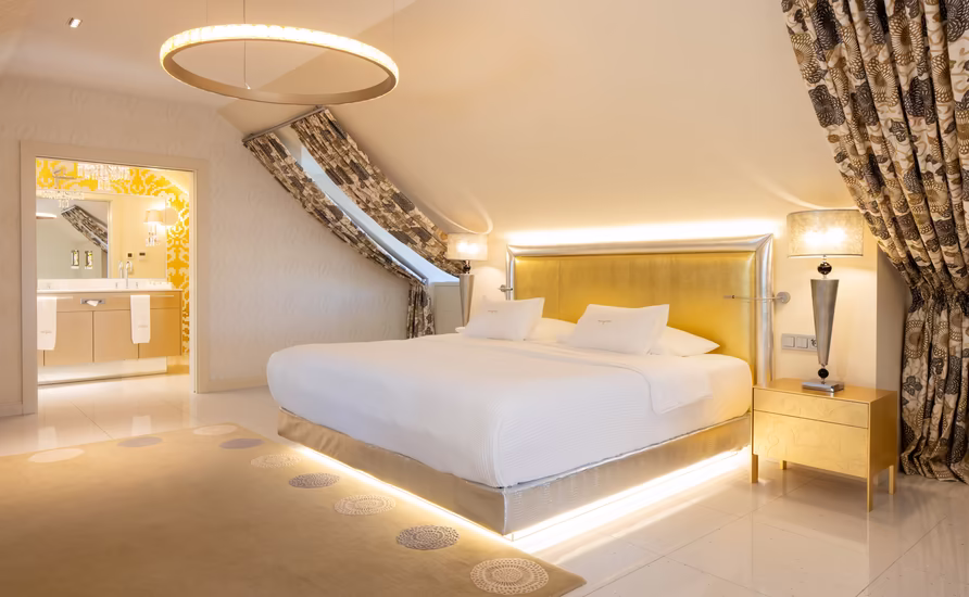 großes Doppelbett mit Dachschräge und goldenen Details 