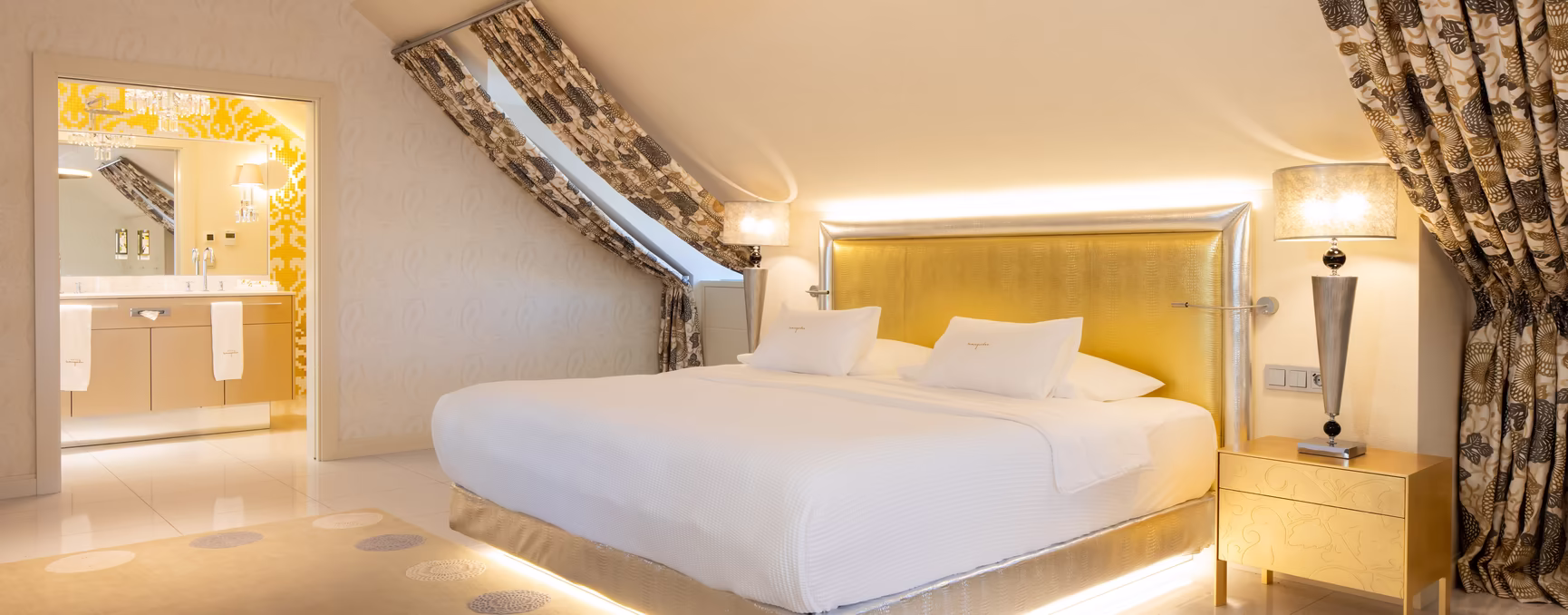 großes Doppelbett mit Dachschräge und goldenen Details 