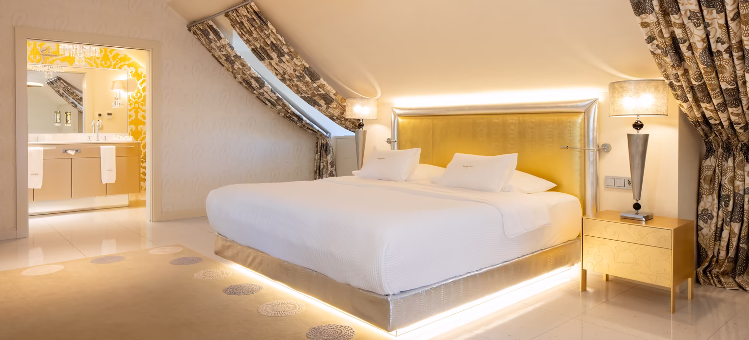 großes Doppelbett mit Dachschräge und goldenen Details 