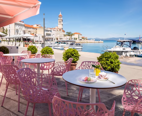 Sitzmöglichkeiten am Meer mit Rosa Stühlen bei Sonnenschein