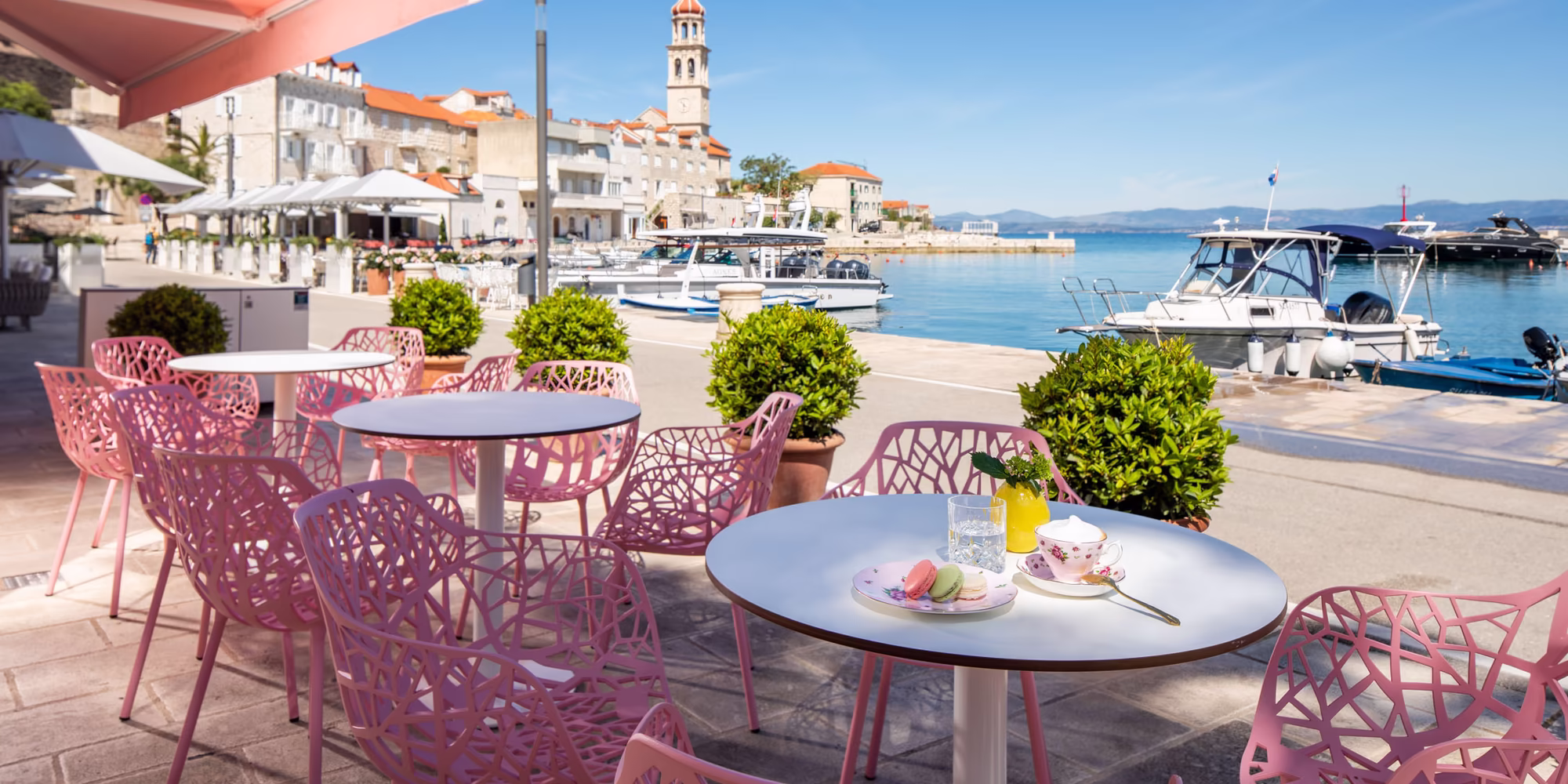Sitzmöglichkeiten am Meer mit Rosa Stühlen bei Sonnenschein