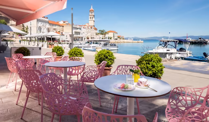 Sitzmöglichkeiten am Meer mit Rosa Stühlen bei Sonnenschein