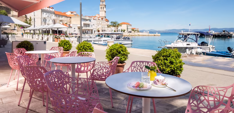 Sitzmöglichkeiten am Meer mit Rosa Stühlen bei Sonnenschein