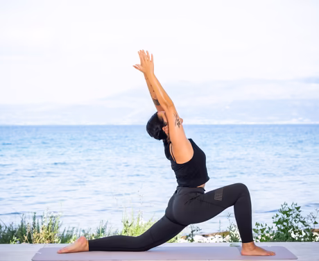 Frau macht Yogafigur am Strand direkt am Meer
