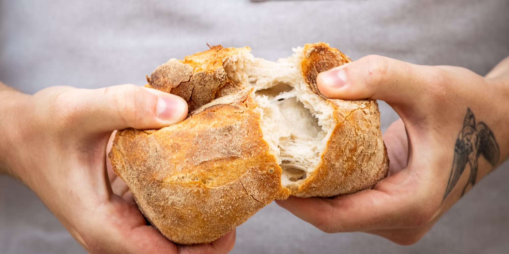 Frisches, knuspriges Brot wird in der Mitte auseinandergebrochen 