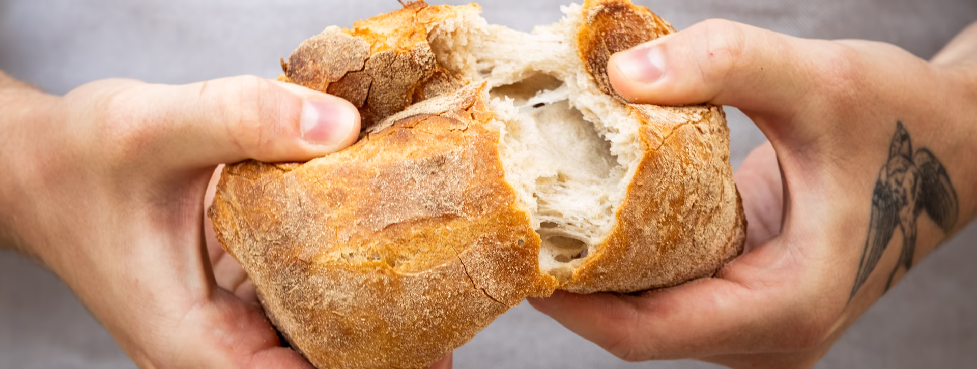 Frisches, knuspriges Brot wird in der Mitte auseinandergebrochen 