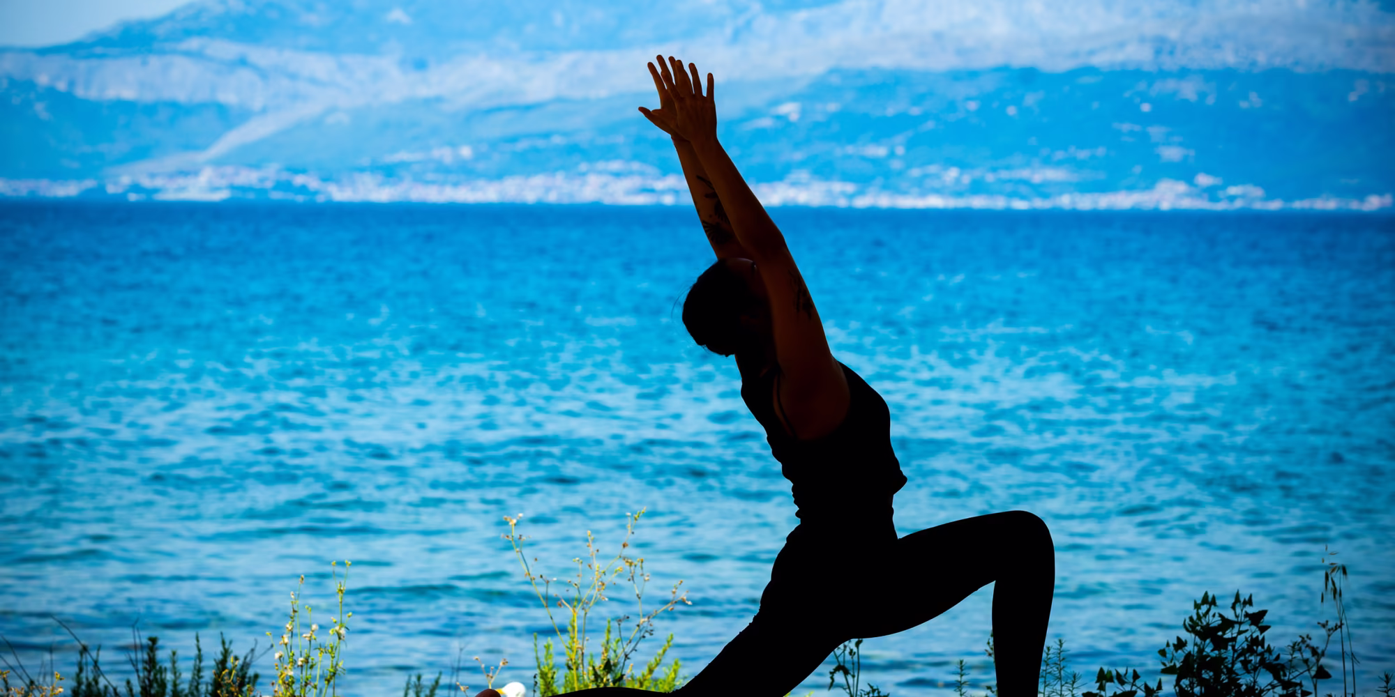 Yoga am Strand mit dem Meer im Hintergrund