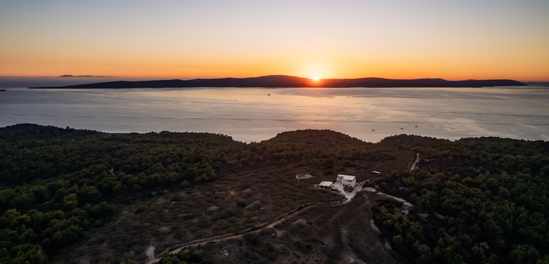 Drohnenaufnahme Olivenhaus bei Sonnenuntergang mit Meer
