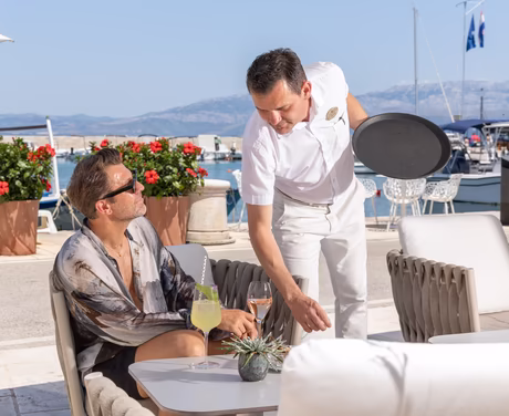 Kellner serviert Mann einen Champagner bei einer Bar am Strand
