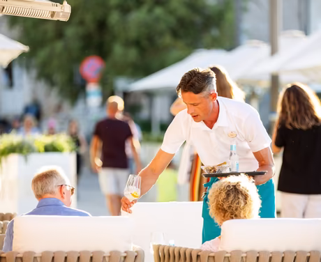 Kellner räumt Getränke von der Außen Bar ab