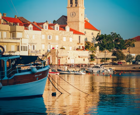 Kroatischer Kirchturm direkt am Hafen bei Sonnenaufgang