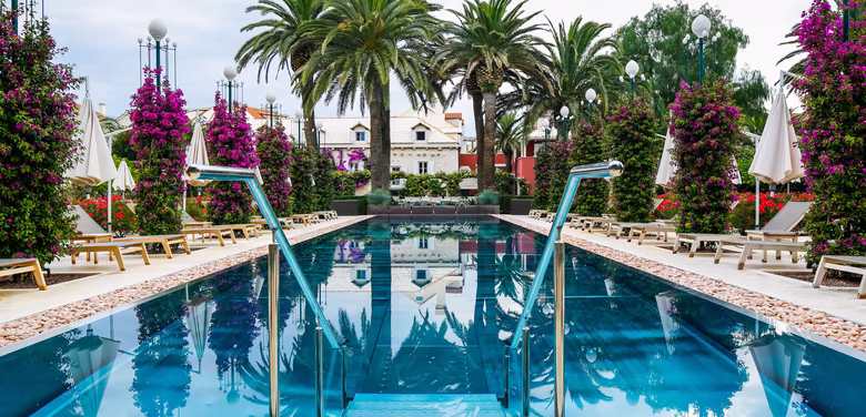 Großer Pool umgeben von vielen Palmen und blühenden Zitronenbäumen 