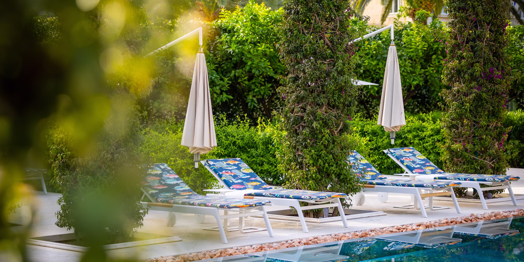 Sonnenliegen mit Schirm vor dem Pool 
