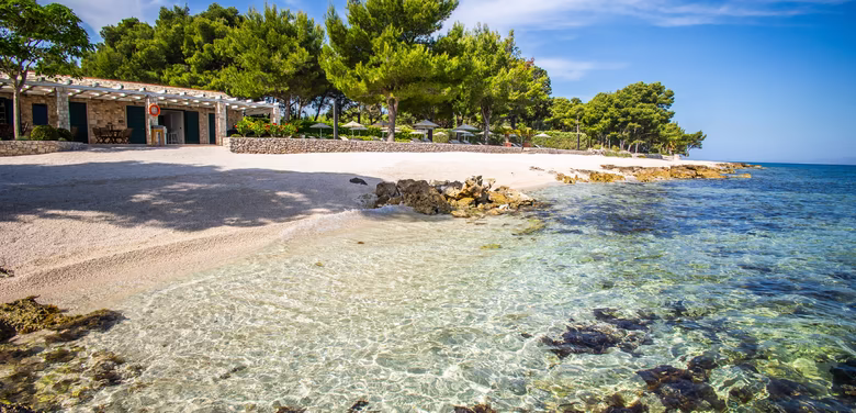kristallklares Wasser mit Kieselstrand, Strandbar und Bäumen