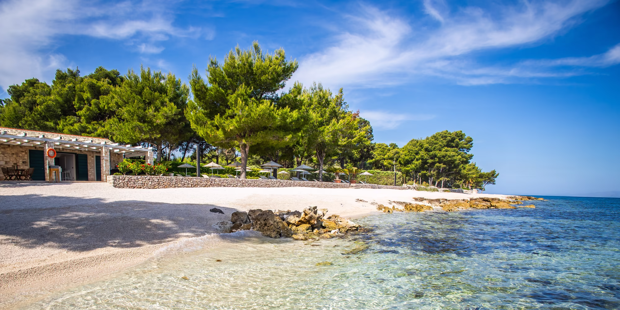 kristallklares Wasser mit Kieselstrand, Strandbar und Bäumen