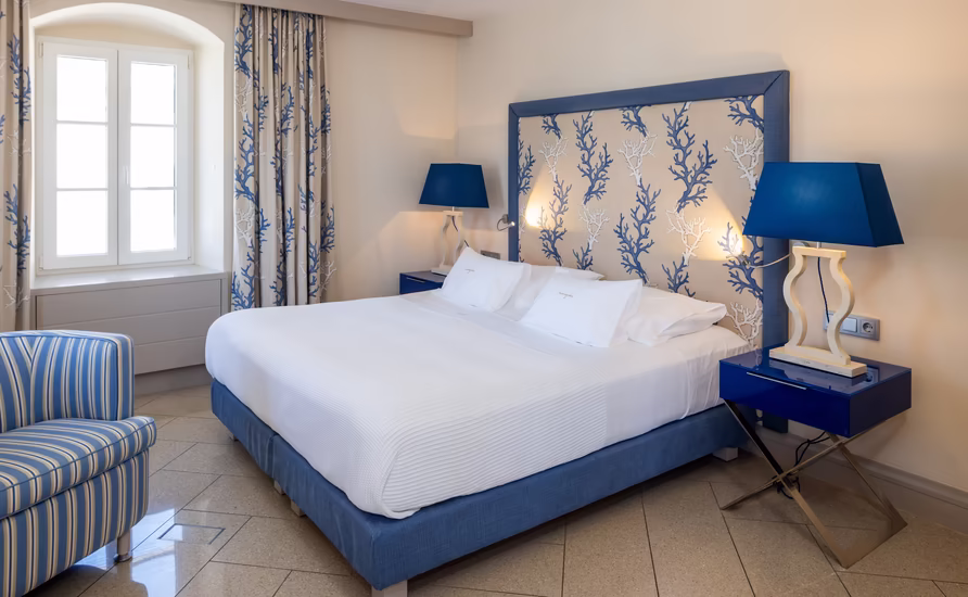 großes Doppelbett mit hoher Kopfstütze im blauen Farbton