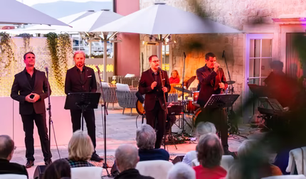 Vier Männer singen am Abend bei einem Event vor dem Hotel