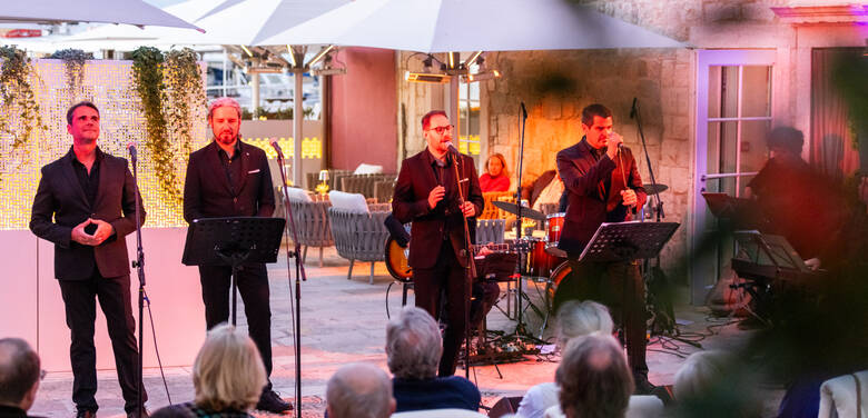 Vier Männer singen am Abend bei einem Event vor dem Hotel