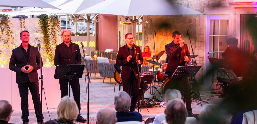 Vier Männer singen am Abend bei einem Event vor dem Hotel