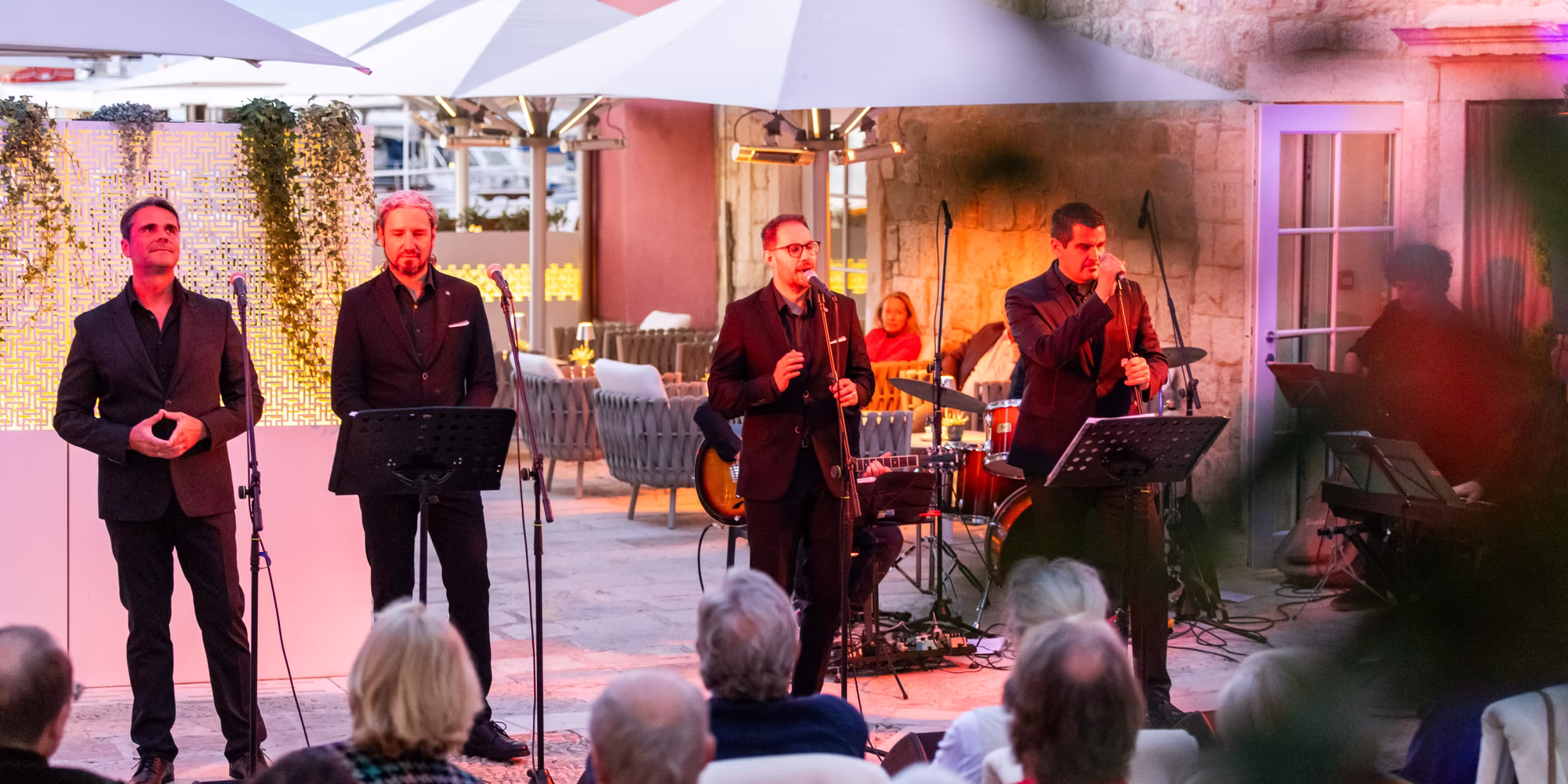 Vier Männer singen am Abend bei einem Event vor dem Hotel