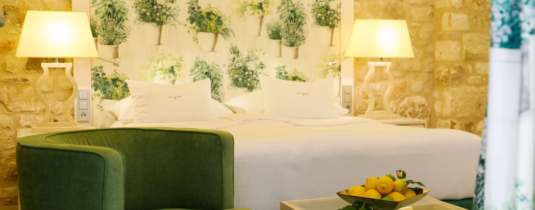 großes Doppelbett mit Sitzgarnitur und kleinem Glastisch in grüner Farbe