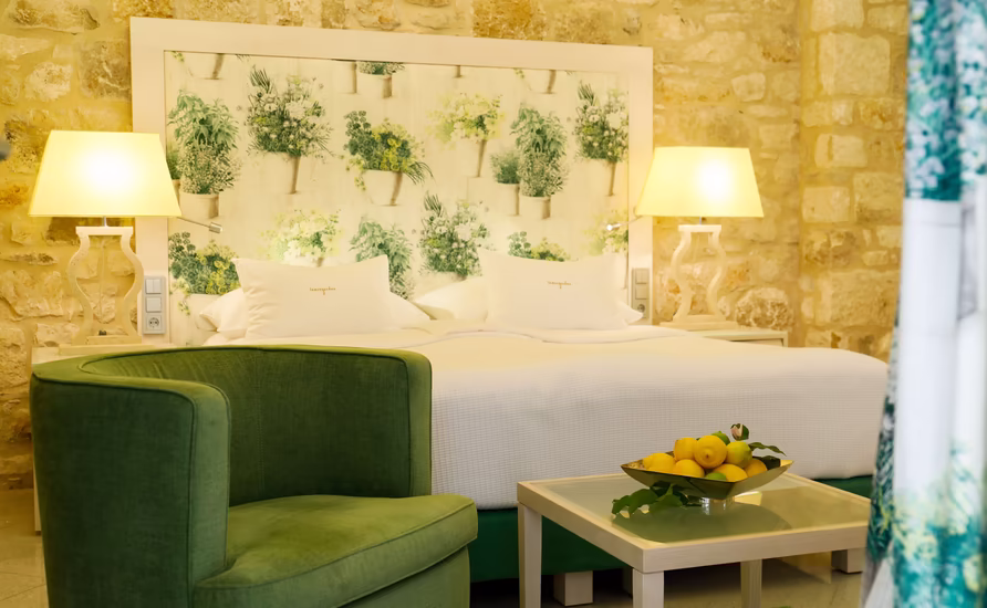 großes Doppelbett mit Sitzgarnitur und kleinem Glastisch in grüner Farbe