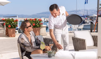 Kellner serviert Mann einen Champagner bei einer Bar am Strand