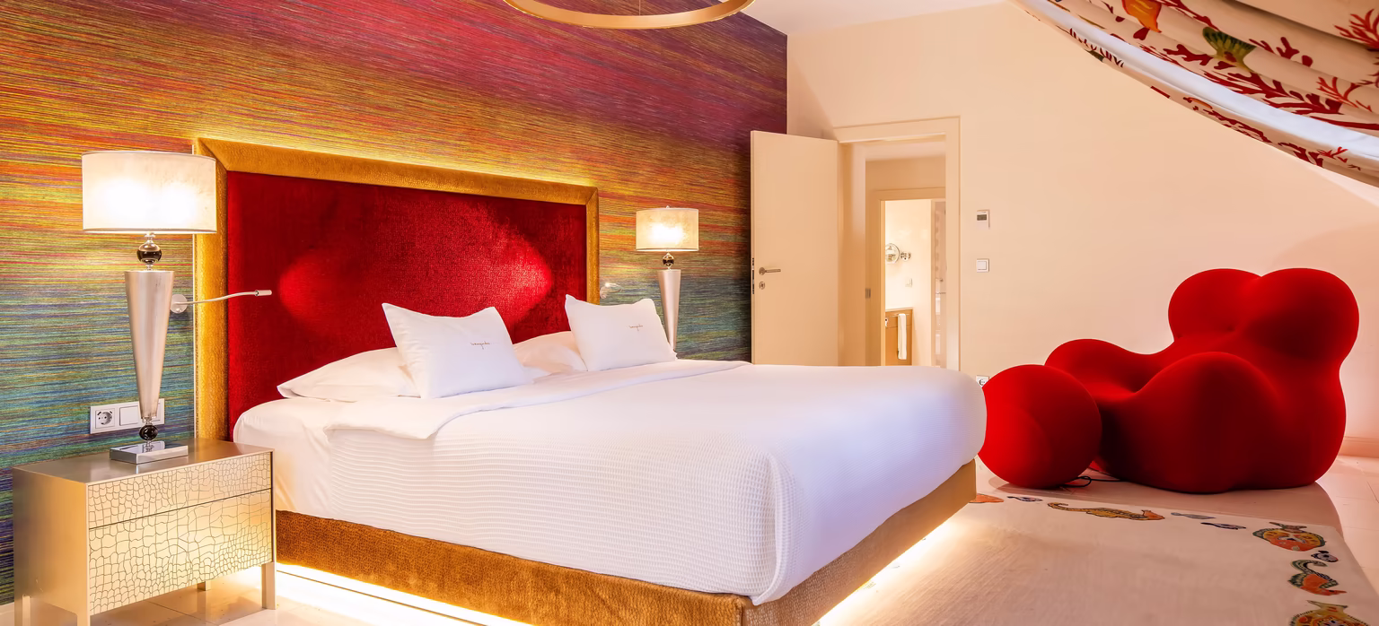 Zimmer im Rotton mit großem Doppelbett und Dachschräge