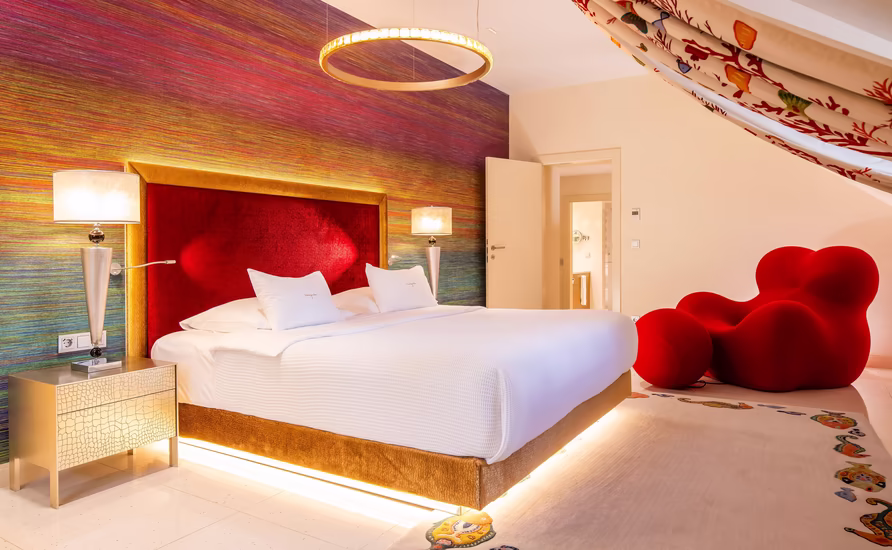 Zimmer im Rotton mit großem Doppelbett und Dachschräge